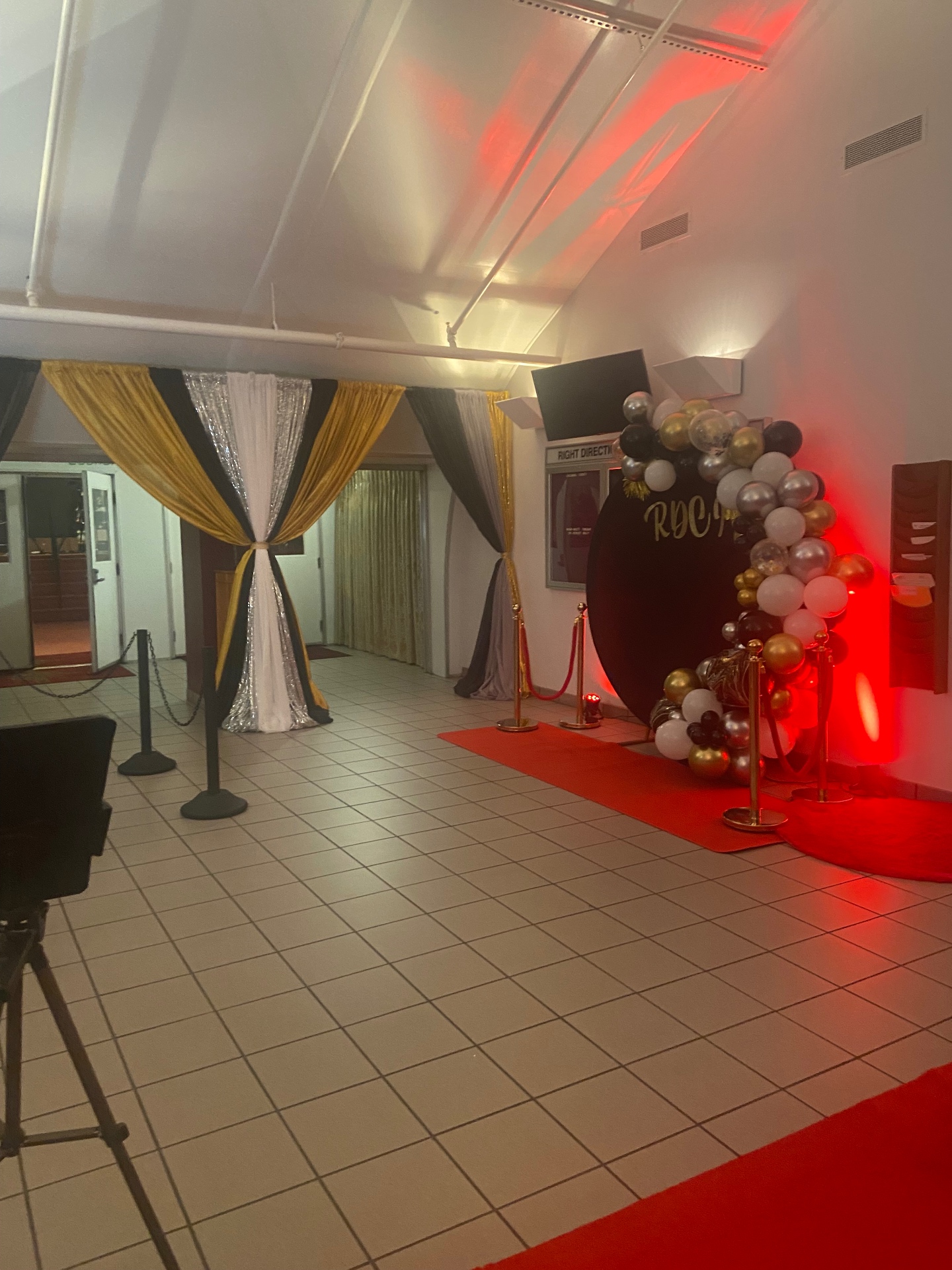 Red Carpet themed lobby design with gold and silver drapes, RDCI backdrop, stanchions and red carpet under stage lighting